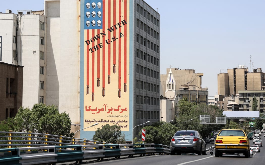 Commuters drive along a bridge near a building bearing a landmark anti-US mural in Tehran, on 22 June 2025.