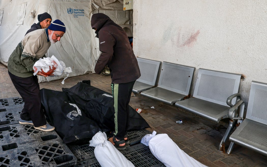 A Palestinian man carries the body of a child of the Abu Slemah family at al-Najar hospital in Rafah in the southern Gaza Strip on March 8, 2024, after their were killed following overnight Israeli air strikes, amid continuing battles between Israel and the Palestinian militant group Hamas. (Photo by MOHAMMED ABED / AFP)