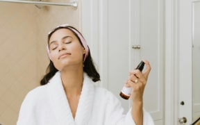 Woman spraying herself in bathroom