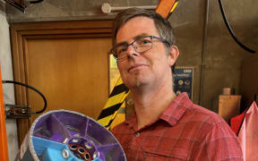 Doctor Andrew Hall holding an acoustic metamaterial system, designed to allow airflow into homes while keeping loud noise out