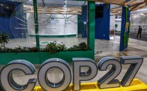 A person walks near the COP27 climate conference at the deserted hall at the Sharm el-Sheikh International Convention Centre, in Egypt's Red Sea resort city of the same name near the end of the climate conference on November 19, 2022. (Photo by AHMAD GHARABLI / AFP)