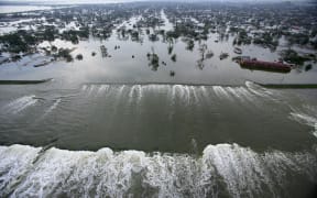 Water spills over a levee along the Inner Harbor Navigational Canal in the aftermath of Hurricane Katrina 30 August, 2005 in New Orleans.