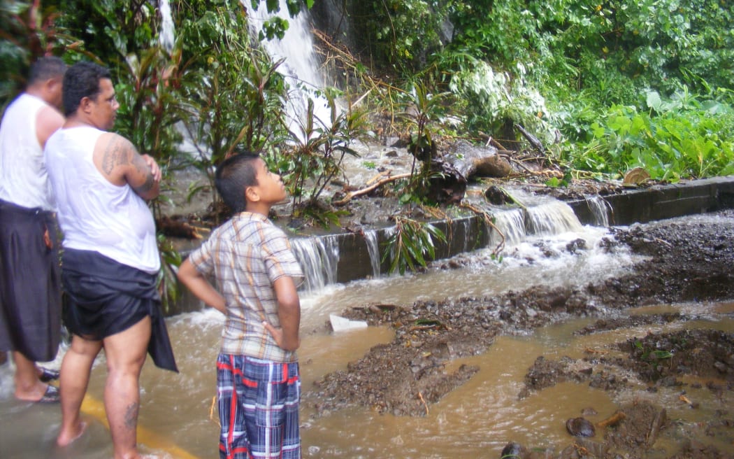 Three individuals survey a small mudslide behind an office building in Fagatogo village. Mud and water made it into the first floor of the two-story building
