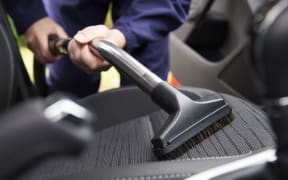 Man vacuuming car seat.