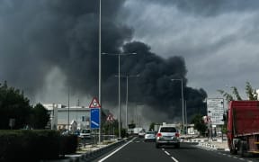 Motorists drive past a plume of smoke rising from a reported Iranian strike in the industrial district of Doha on March 1, 2026. US President Donald Trump said on February 28 that Iran's supreme leader Ayatollah Ali Khamenei was dead, after Israel and the United States launched an attack of unprecedented scale aimed at bringing down the Islamic republic. (Photo by Mahmud HAMS / AFP)
