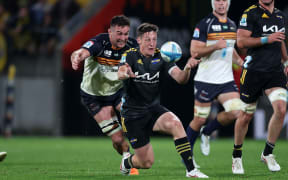 Hurricanes halfback Cameron Roigard clears the ball under pressure.
