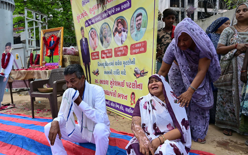 The mother (bottom R) of Air India Flight 171 plane crash victim Akash Patni grieves at the crash site on the first anniversary of the disaster in Ahmedabad on June 12, 2026. India’s aviation accident probe agency is facing renewed criticism from pilot groups ahead of the anniversary of the 2025 Air India Boeing-787 crash in Ahmedabad, which killed 260 people. (Photo by Shammi MEHRA / AFP)