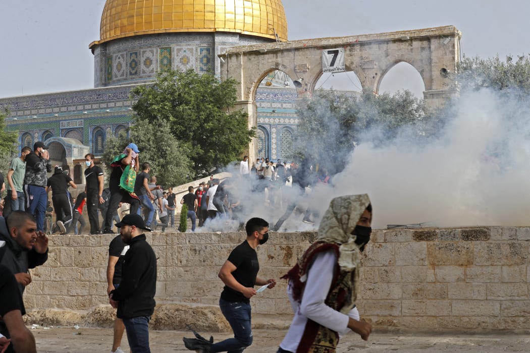 Palestinian protesters run for cover from tear gas fired by Israeli security forces amid clashes at Jerusalem's Al-Aqsa mosque compound on 10 May 2021.