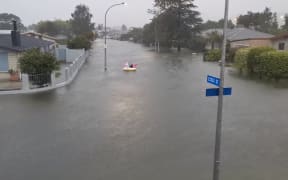 A man paddles an inflatable unicorn up the road, on Essex Street, Napier.