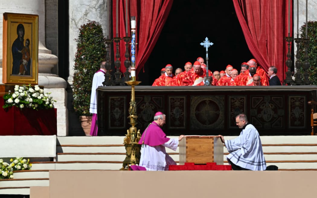 Master of Pontifical Liturgical Celebrations, Italian Archbishop Diego Ravelli (L) kneels before the coffin of late Pope Francis during his funeral ceremony in St Peter's Square, at the Vatican, on April 26, 2025. (Photo by Andreas SOLARO / AFP)