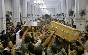 Egyptian mourners carry the coffins of the victims killed in Cairo Coptic Abu Sifin church fire, during a funeral at the church of the Blessed Virgin Mary in Giza on 14 August 2022.