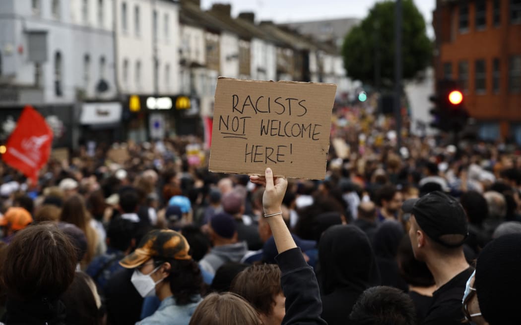 A protester holds a placard reading "Racists not welcome here" during a counter demonstration against an anti-immigration protest called by far-right activists in the Walthamstow suburb of London on August 7, 2024. Thousands of anti-racism protesters took to the streets in several English cities on Wednesday to oppose violent far-right demonstrations that have gripped the country in recent days. (Photo by BENJAMIN CREMEL / AFP)