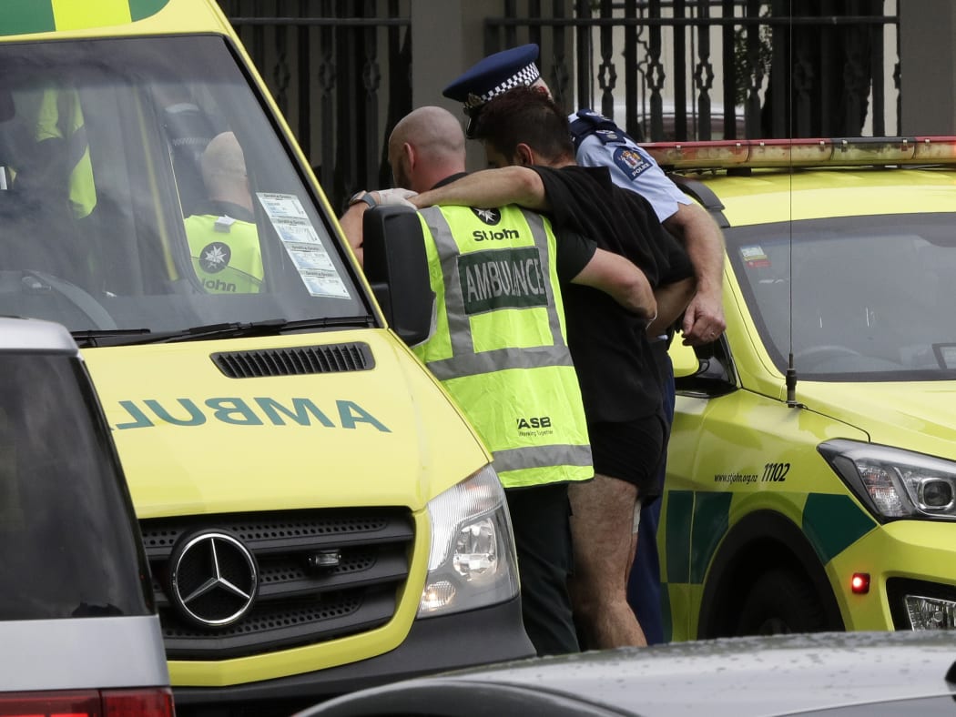 Police and ambulance staff help a wounded man from outside a mosque in central Christchurch, New Zealand, Friday, March 15, 2019.  A witness says many people have been killed in a mass shooting at a mosque in the New Zealand city of Christchurch. (AP Photo/Mark Baker)
