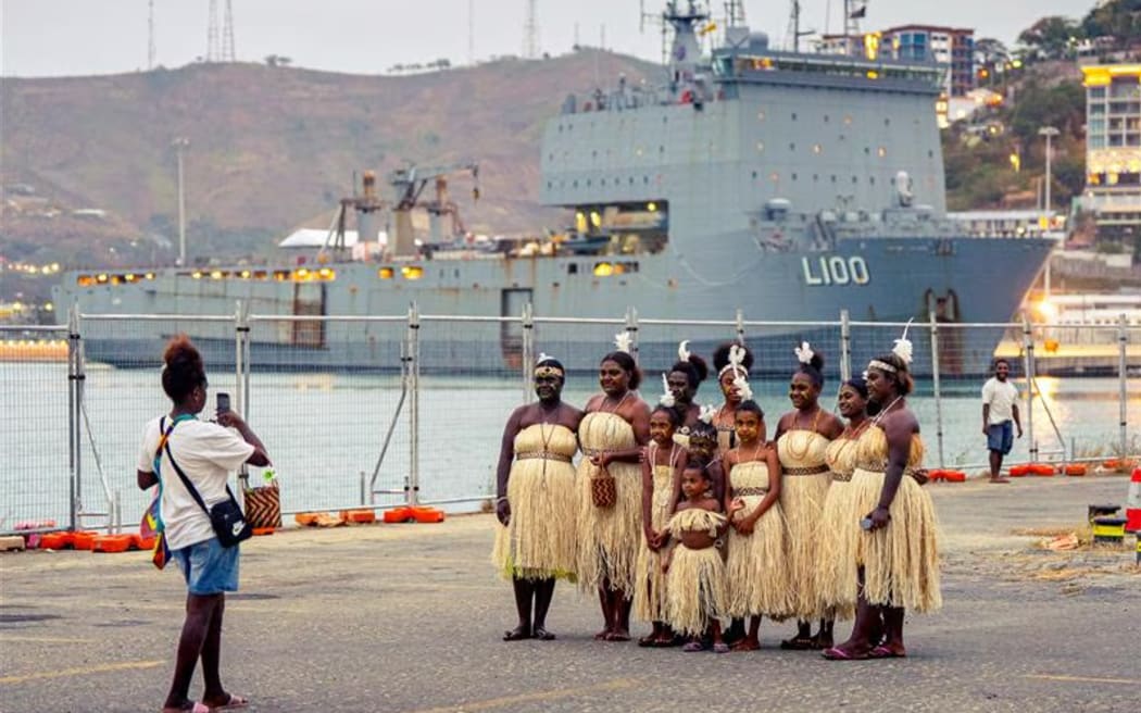 Traditional dancers pose for photos in front of an Australian warship docked in Port Moresby Harbour. (ABC News)