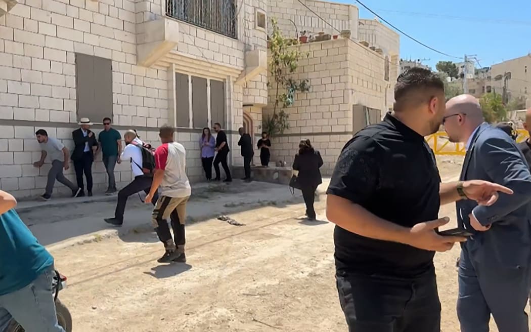 This frame grab from AFPTV footage shows members of a diplomatic delegation from the European Union reacting after shots were fired as they gathered in the eastern entrance of Jenin camp during a visit to the city of Jenin, on 21 May, 2025, amid an ongoing Israeli military offensive in the occupied West Bank.