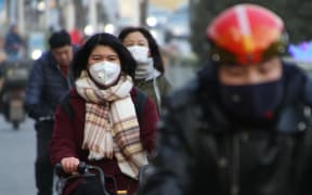 People wearing masks ride bycicles in Beijing, China on Jan. 21, 2020. Wuhan city announced that another patient had died due to the mysterious SARS-like virus on the previous day.