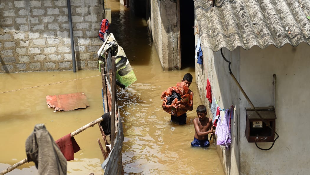 Sri Lankan youths wade through floodwaters as they go about their daily chores.