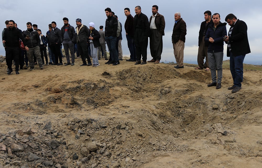 Residents look at a crater caused by a missile launched by Iran on US-led coalition forces on the outskirts of Duhok, Iraq.