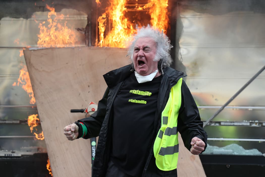 A Yellow Vest protester gestures in front of a newsstand set alight during clashes with riot police forces on the Champs-Elysees in Paris on March 16.