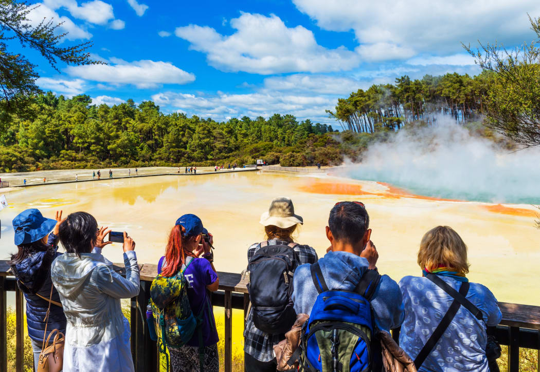 A group of people visiting the geothermal pools in Wai-O-Tapu park.