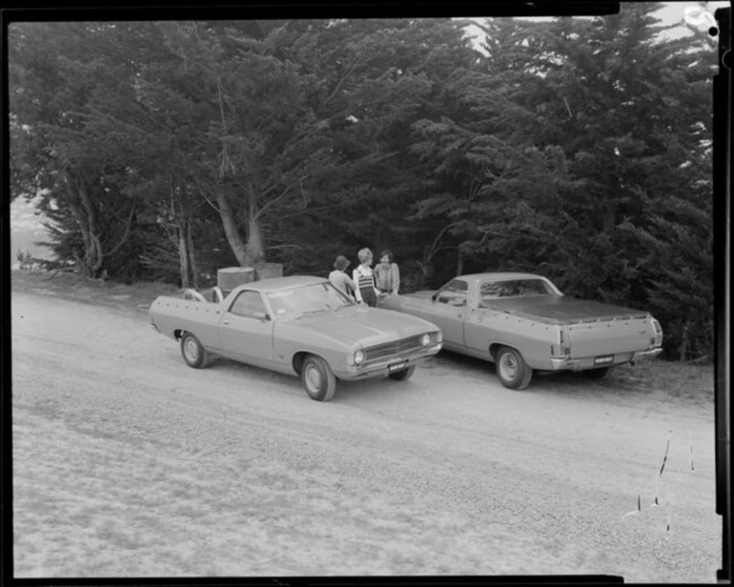 People talking next to two Ford Falcon utes (pick up truck),