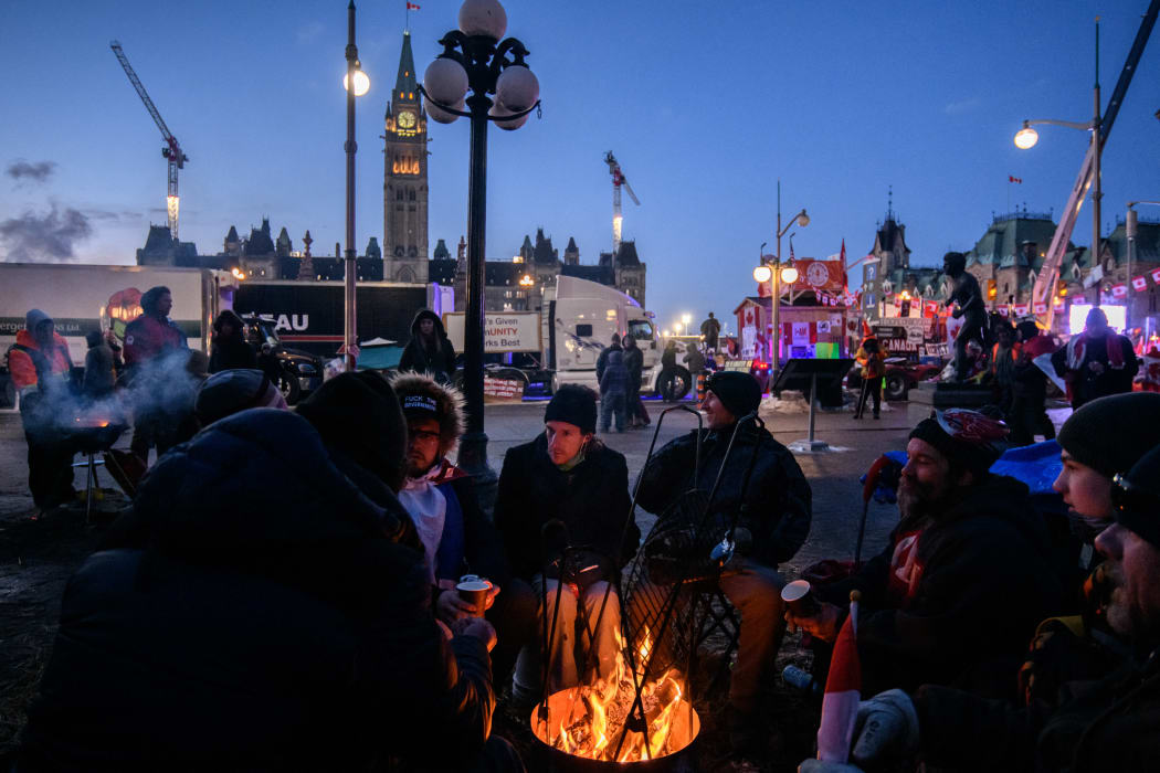 Demonstrators gather around a fire during a protest by truck drivers over pandemic health rules and the Trudeau government, outside the parliament of Canada in Ottawa on 13 February, 2022.