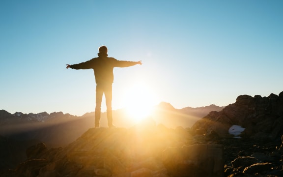 Man standing in New Zealand mountains at sunrise