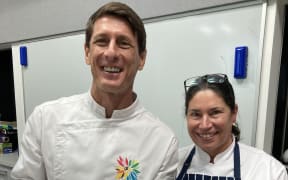 A head and shoulders shot of chef Gaby Levionnois (left) holding a dish with a fish on it and AUT's professor of Food Studies Tracy Berno (right)