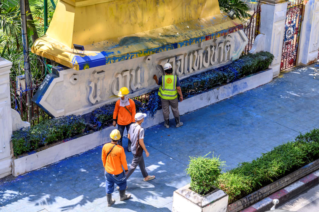 Workers inspect the damage of the paint-splashed wall of the Royal Thai Police Headquarters.