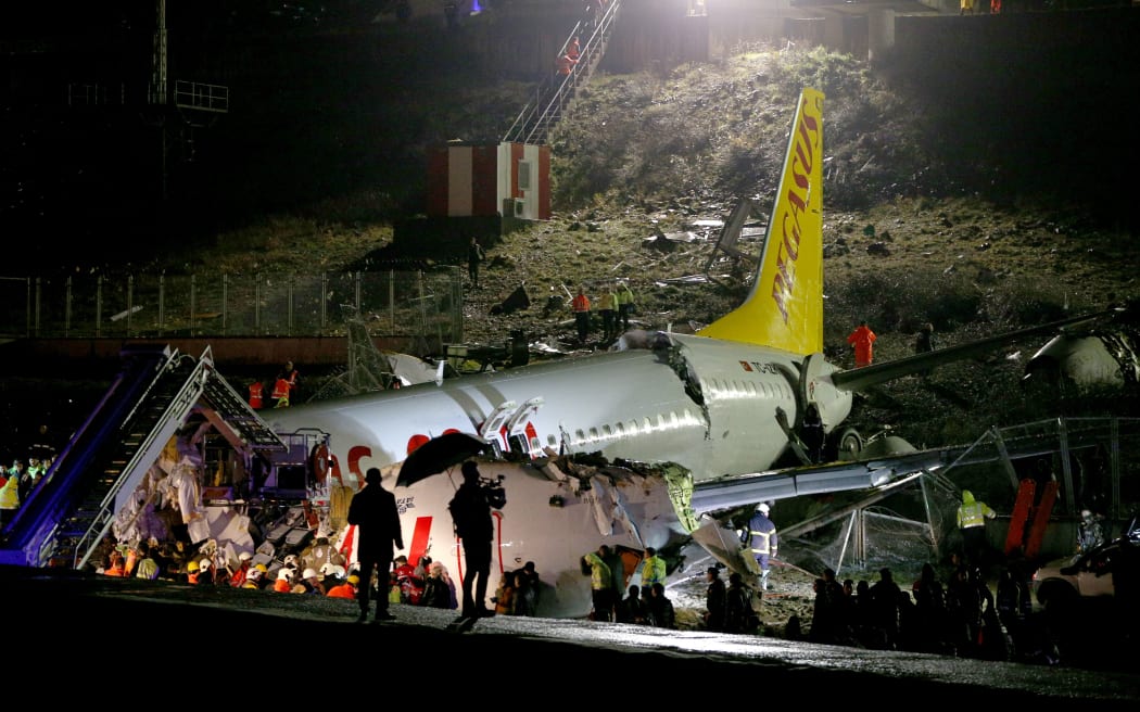 Health teams and fire brigade crews are seen near debris of a passenger plane after skidded off the runway in Istanbul Sabiha Gokcen International Airport, breaking into two, on February 05, 2020 in Istanbul, Turkey.