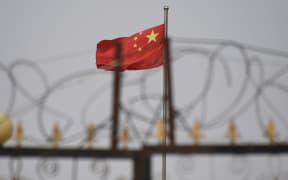 TOPSHOT - This photo taken on June 4, 2019 shows the Chinese flag behind razor wire at a housing compound in Yangisar, south of Kashgar, in China's western Xinjiang region. - A recurrence of the Urumqi riots which left nearly 200 people dead a decade ago is hard to imagine in today's Xinjiang, a Chinese region whose Uighur minority is straitjacketed by surveillance and mass detentions. A pervasive security apparatus has subdued the ethnic unrest that has long plagued the region. (Photo by GREG BAKER / AFP) (Photo by GREG BAKER/AFP via Getty Images)