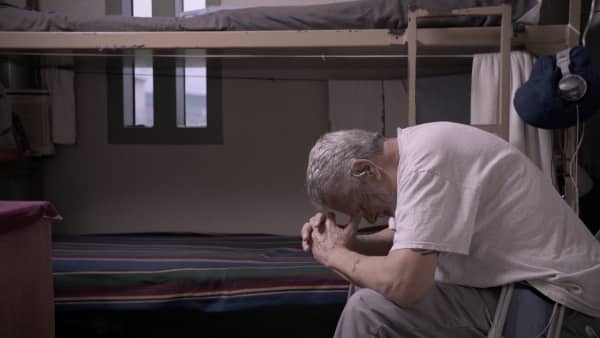 Missouri maximum security prisoner Jimmy, in the Netflix documentary The Quilters, is bent forward with his hands on his head.