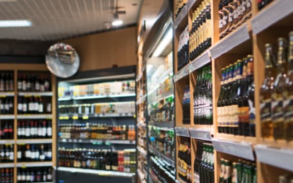 Blurred image of shelves with alcoholic drinks in supermarket.