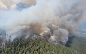 Large plumes of smoke over Canadian forest as firefighters battle flames.