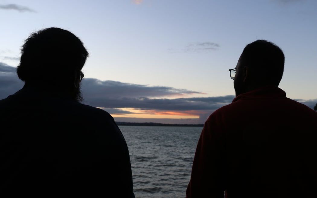 Two Muslims looking out at the coastal horizon during sunset at Point Chevalier's Coyle Park.