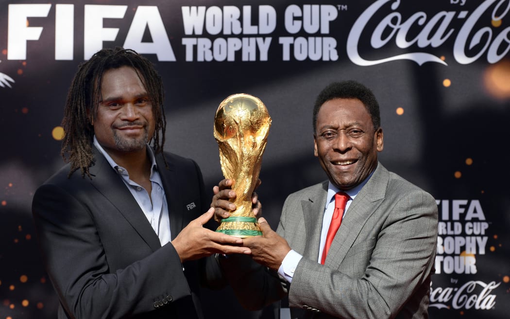 Brazilian football legend Pele (R) and former French international football player Christian Karembeu pose with the FIFA World Cup trophy during the FIFA World Cup Trophy Tour on March 9, 2014 outside the Hotel de Ville in Paris. The FIFA World Cup trophy arrived with its ambassador Pele in Paris on March 9, 2014 and will be exhibited on the Hotel de Ville plaza until March 10. This event kicks off the festivities of the FIFA World Cup 2014, that will be held in Brazil through June 12-July 13, 2014. AFP PHOTO / FRANCK FIFE (Photo by FRANCK FIFE / AFP)