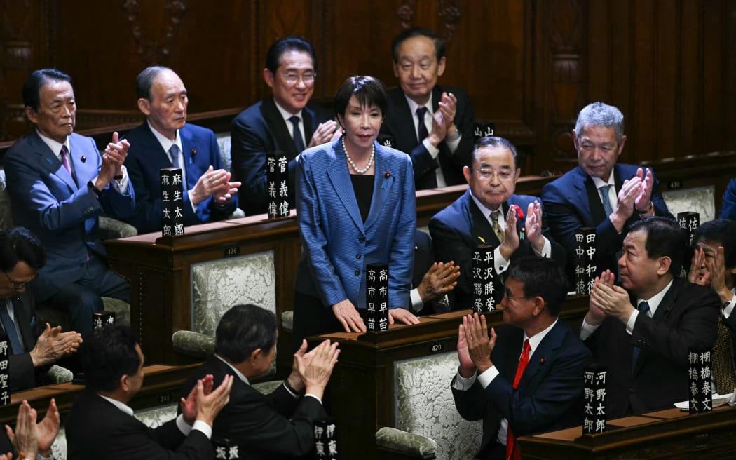Liberal Democratic Party (LDP) President Sanae Takaichi stands up to acknowledge the applause after she was selected as Japan's new prime minister during an extraordinary session of the lower house of parliament in Tokyo on October 21, 2025.  (Photo by Philip FONG / AFP)