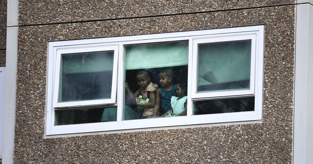 Residents look from a window at one of nine public housing estates locked down due a spike in COVID-19 coronavirus numbers in Melbourne on July 6, 2020.