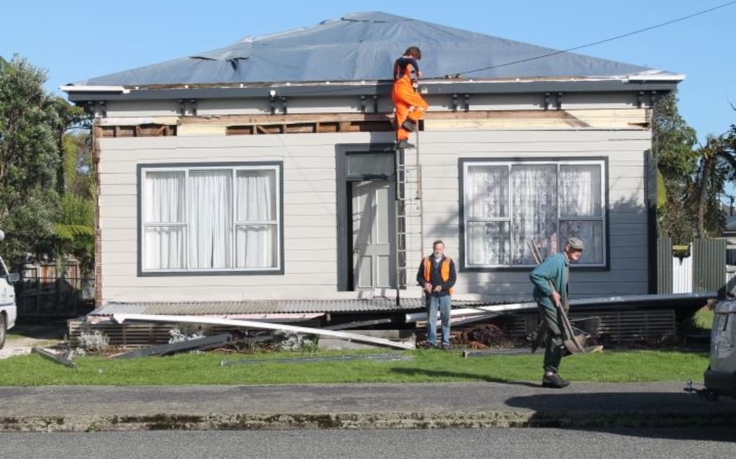 William Lomax-Sawyer on ladder and Ash Bradley from Buller Electricity restore power to one of the thousands of homes which lost power.