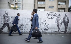 Iranians walk past mural in Tehran on May 8.