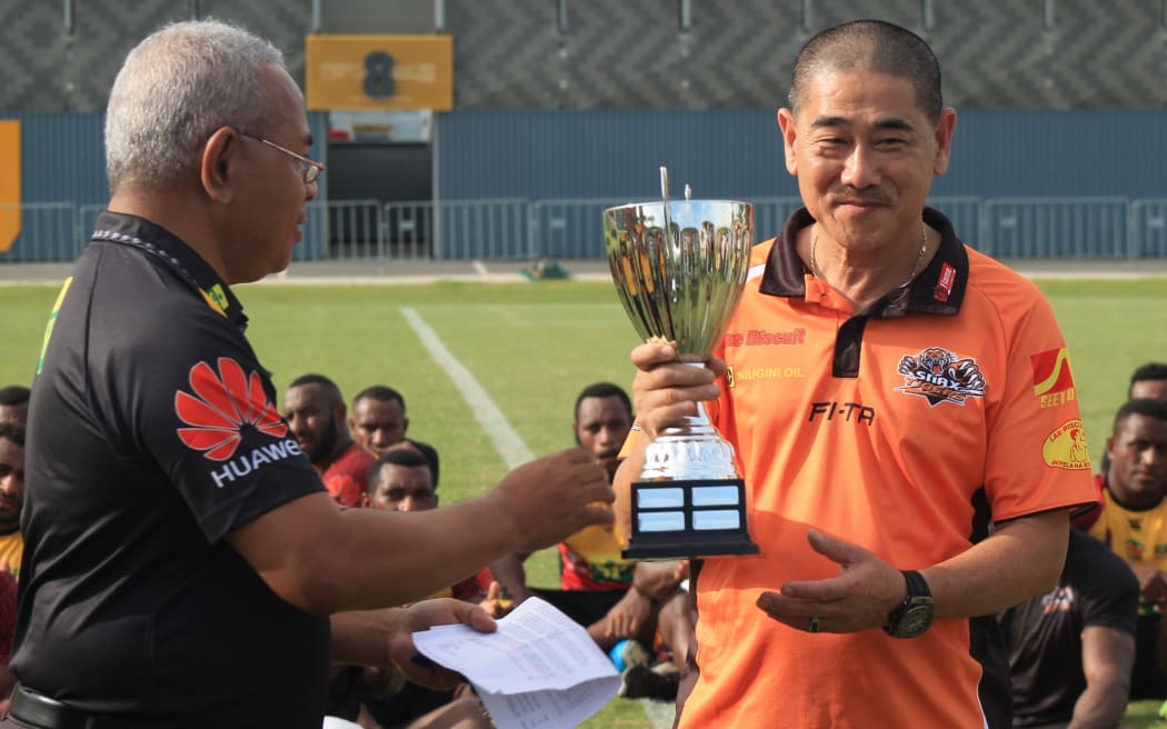 PNG Rugby League CEO Reatau Rau handing over the Melenesian Cup to Lae Snax Tigers Sponsor Ian Chow.