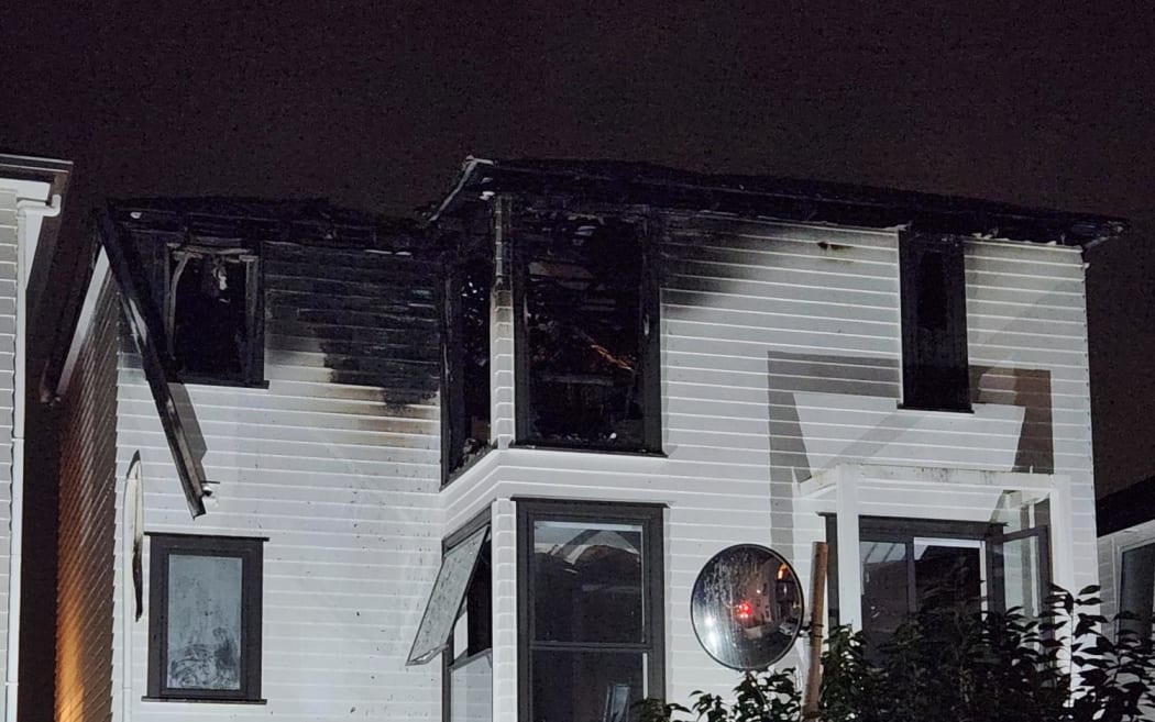 A three-story apartment block with the top storey charred and blackened.