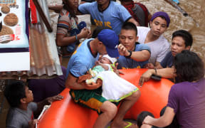 Policemen ecavuate a baby in Cagayan City on Friday 22 December 2017, after the Cagayan River swelled from heavy rains brought by Tropical Storm Tembin.