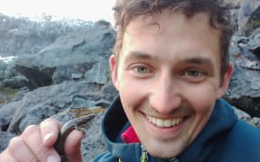 Sam Purdie holding an awakōpaka skink