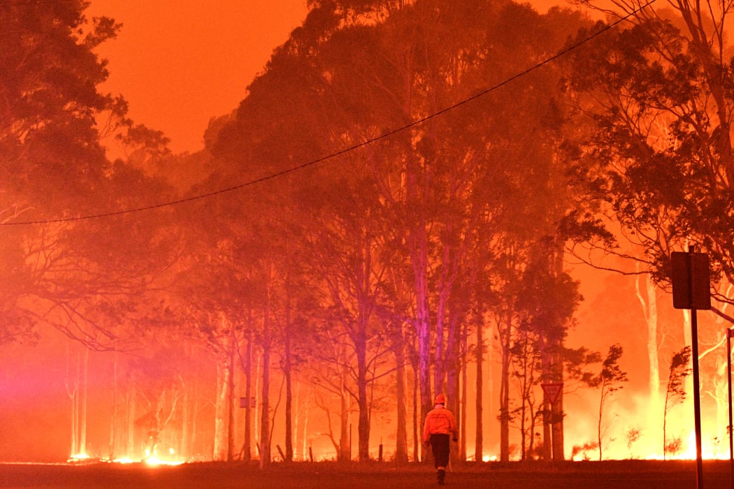 A firefighter walks past burning trees during a battle against bushfires around the town of Nowra in the Australian state of New South Wales on December 31, 2019.
