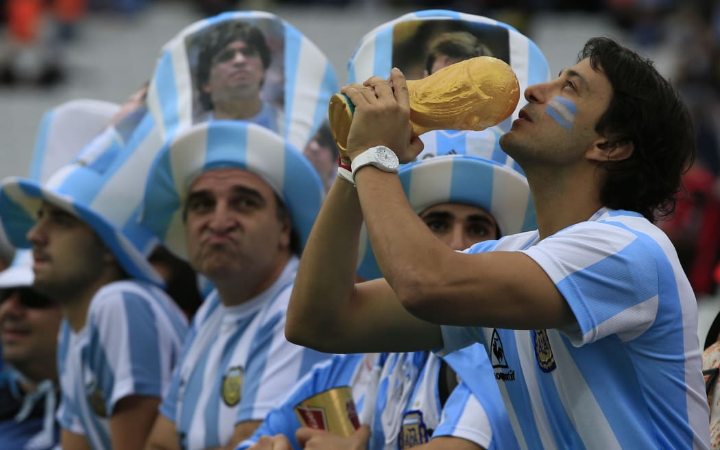 An Argentinian fan holds a replica of the world cup trophy at The Corinthians Arena in Sao Paulo.