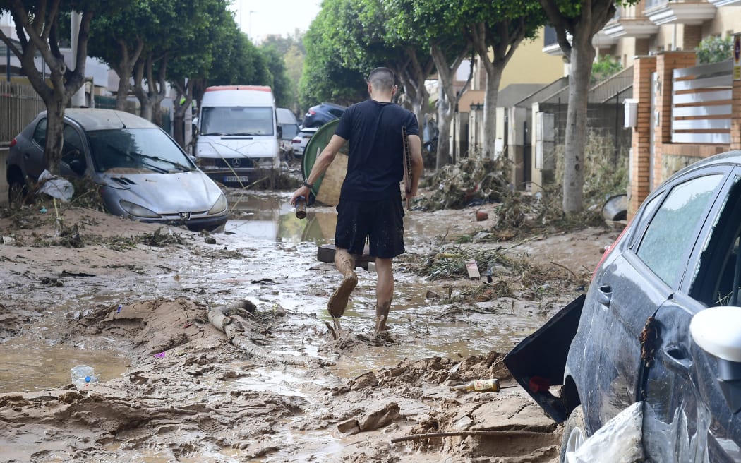 A man walks in a street covered in mud in a flooded area in Picanya, near Valencia, eastern Spain, on October 30, 2024. - Floods triggered by torrential rains in Spain's eastern Valencia region has left 51 people dead, rescue services said on October 30. (Photo by Jose Jordan / AFP)