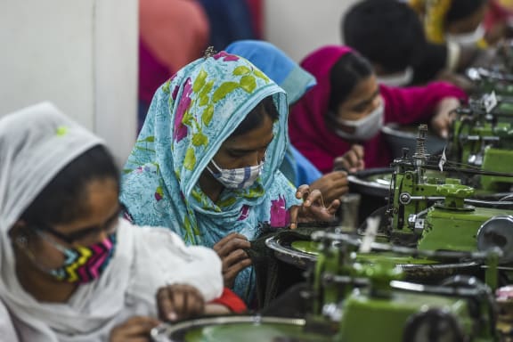 Labourers wearing facemasks work in a garment factory during a government-imposed lockdown as a preventative measure against the COVID-19 coronavirus in Asulia, on the outskirts of Dhaka on April 7, 2020.