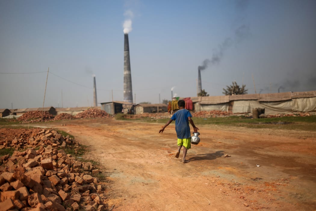 A child is carries drinking water for a brickyard worker.