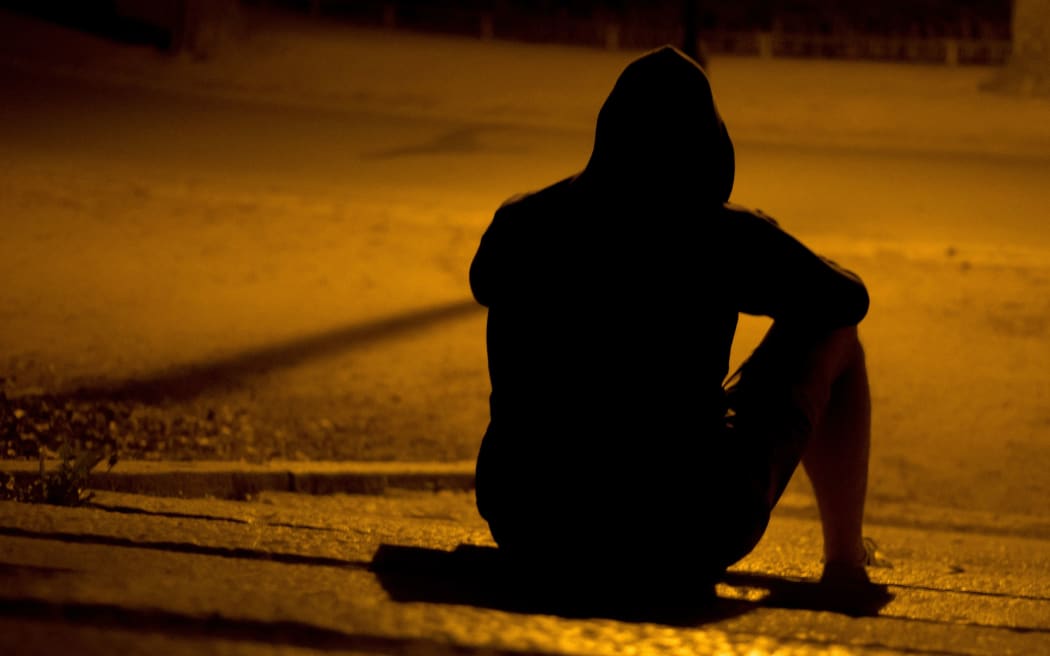 Silhouette of seated man wearing a hoodie.